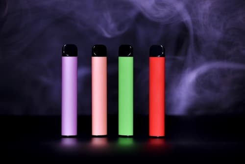 disposable vaporizers lined up in front of purple vapor